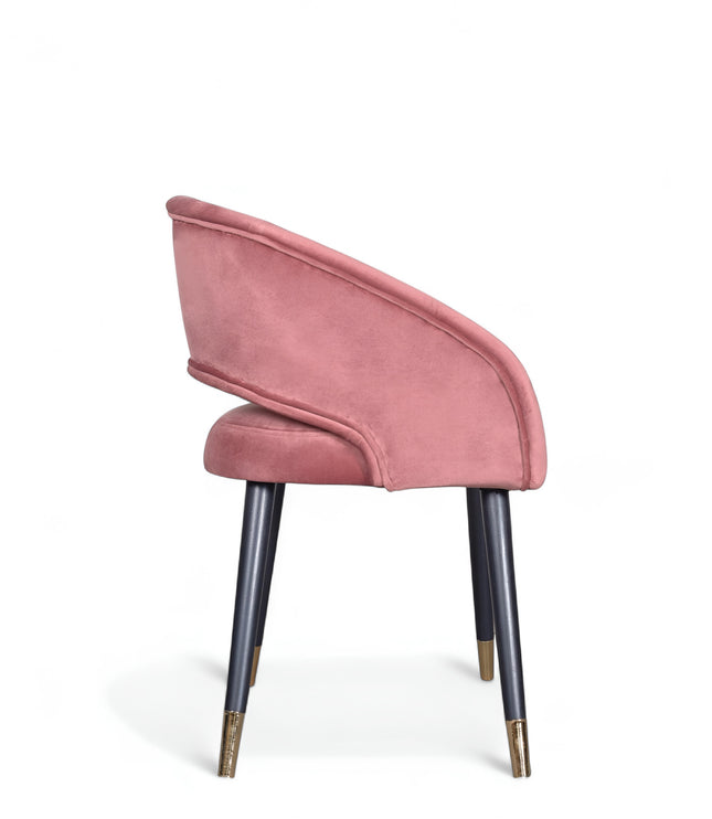 Curved-back pink modern chair with wraparound design, cushioned seat, and brass-tipped black legs