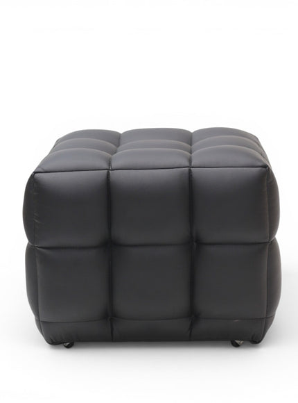A modern black tufted cube ottoman with a padded, segmented design and small black feet, shown against a plain white background.
