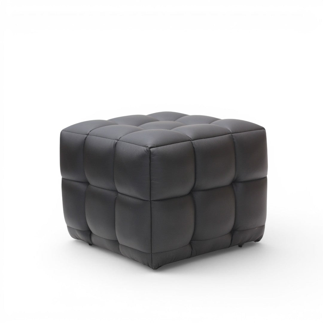 A modern square ottoman with a tufted grid pattern, upholstered in dark charcoal gray leather, shown on a clean white background.