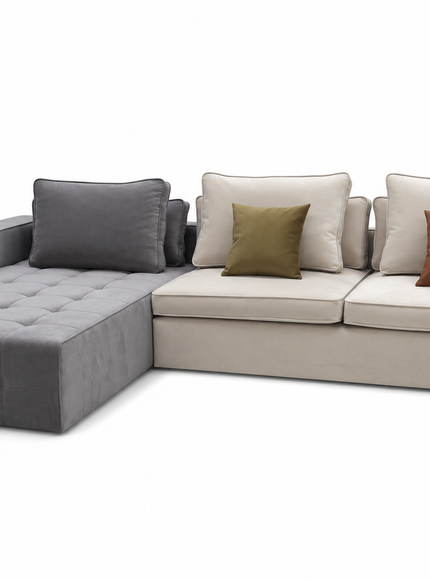 A modern L-shaped sectional sofa with a tufted chaise ottoman on the left, upholstered in light beige fabric with a dark gray accent section. It is styled with multiple throw pillows, including two beige pillows, one olive green pillow, and one terracotta brown pillow, set against a plain white background.