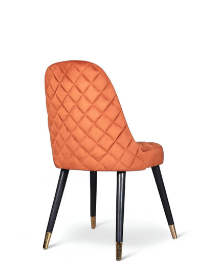 Modern armless orange chair with quilted seat, curved back, and black legs with gold metal tips