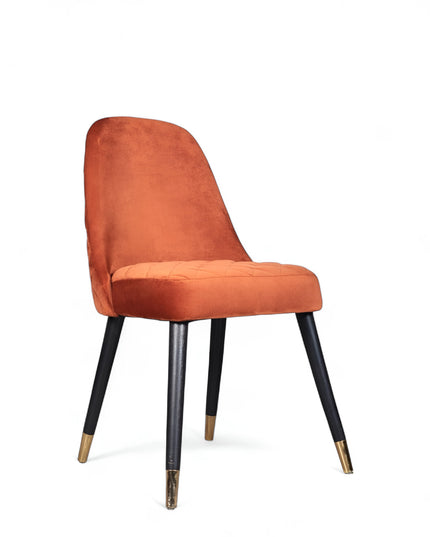 Modern armless orange chair with quilted seat, curved back, and black legs with gold metal tips