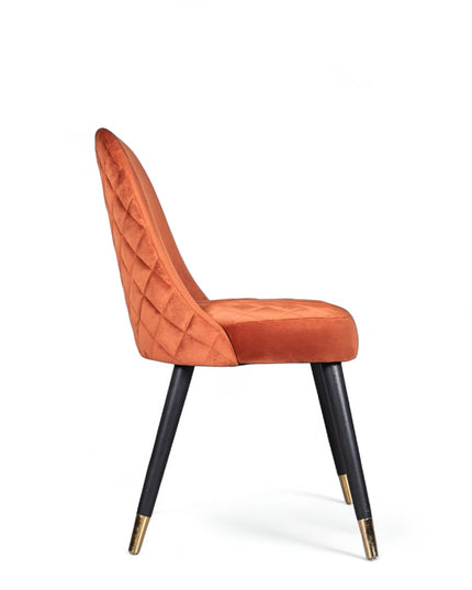 Modern armless orange chair with quilted seat, curved back, and black legs with gold metal tips