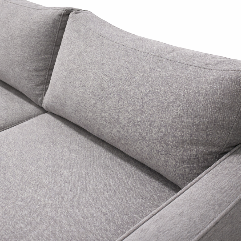 closeup of light gray fabric sectional sofa, highlighting the textured upholstery, plush back cushion, and clean stitched seams under soft, even lighting.
