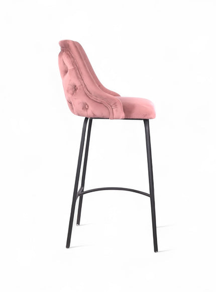 Modern bar stool with a high backrest and seat upholstered in blush pink velvet, featuring button-tufted detailing and slim black metal legs with a built-in footrest, ideal for kitchen islands or contemporary bar spaces
