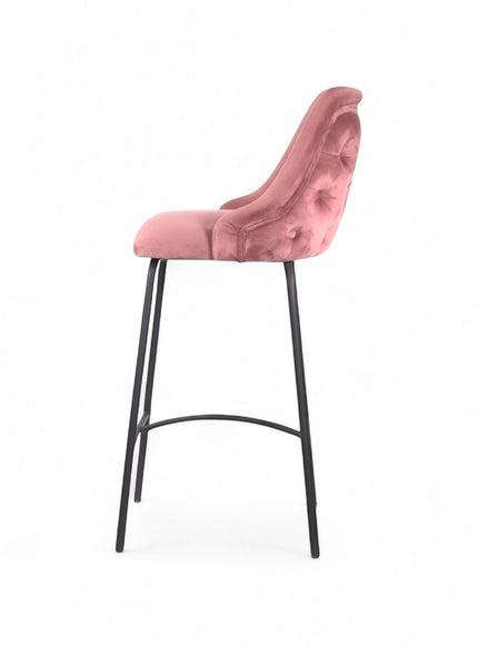 Modern bar stool with a high backrest and seat upholstered in blush pink velvet, featuring button-tufted detailing and slim black metal legs with a built-in footrest, ideal for kitchen islands or contemporary bar spaces
