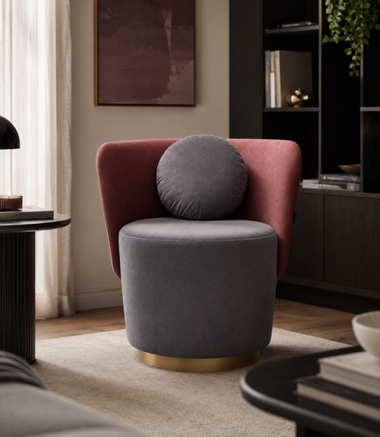 A modern accent chair in a styled living room, featuring a dusty rose velvet armchair with a round gray lumbar pillow and a cylindrical gray velvet seat on a gold-finished base.