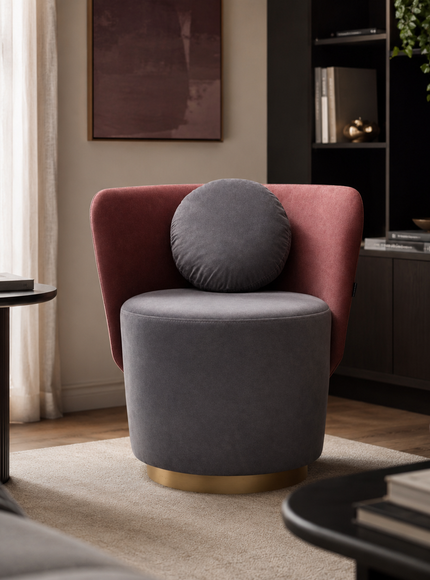 A modern accent chair in a styled living room, featuring a dusty rose velvet armchair with a round gray lumbar pillow and a cylindrical gray velvet seat on a gold-finished base.
