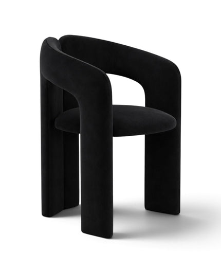A modern black velvet dining chair with a curved, sculptural backrest and thick blocky legs, shown on a clean white background.