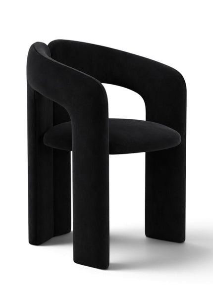 A modern black velvet dining chair with a curved, sculptural backrest and thick blocky legs, shown on a clean white background.