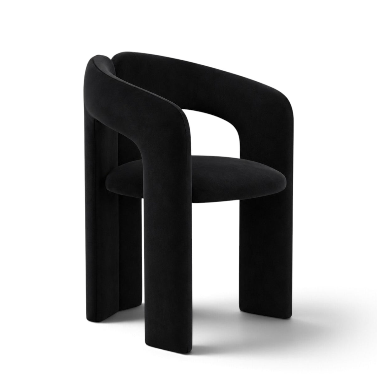 A modern black velvet dining chair with a curved, sculptural backrest and thick blocky legs, shown on a clean white background.