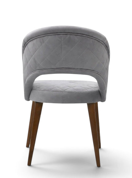 Argent grey upholstered dining chair with curved open backrest, diamond-quilted seat and brown wooden legs.