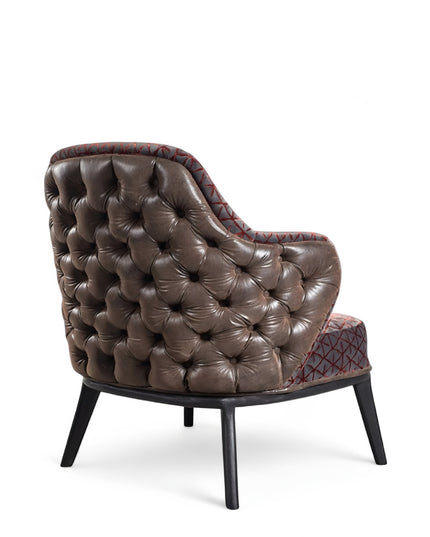 Array armchair with geometric fabric upholstery, deep button-tufted leather-look back, and black tapered wooden legs.