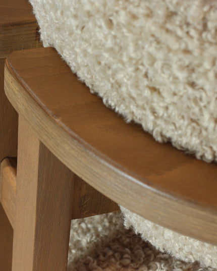 Modern wooden chair with beige boucle upholstery, featuring cushioned seat, rounded backrest, and minimalist armrests.