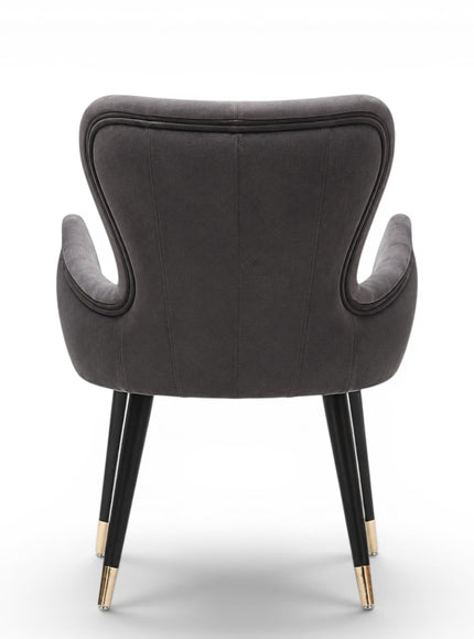 A modern gray velvet dining chair with black tapered legs and gold-toned metal tips, shown against a plain white background.