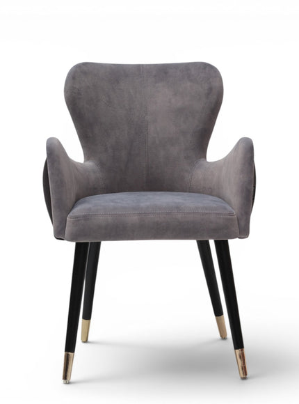 A modern gray velvet dining chair with black tapered legs and gold-toned metal tips, shown against a plain white background.