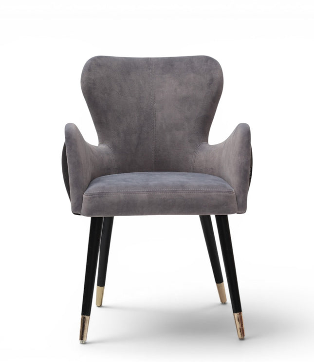A modern gray velvet dining chair with black tapered legs and gold-toned metal tips, shown against a plain white background.