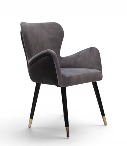 A modern gray velvet dining chair with black tapered legs and gold-toned metal tips, shown against a plain white background.