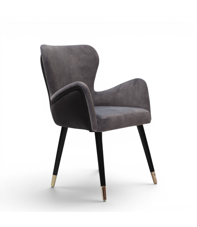 A modern gray velvet dining chair with black tapered legs and gold-toned metal tips, shown against a plain white background.