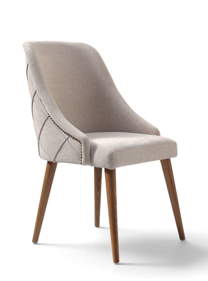 A modern upholstered dining chair with a light beige fabric seat and curved backrest, featuring geometric stitched detailing on the side, supported by four tapered wooden legs, shown on a white background.