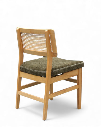 Close-up of a wooden chair with a woven rattan backrest and a textured green upholstered seat.