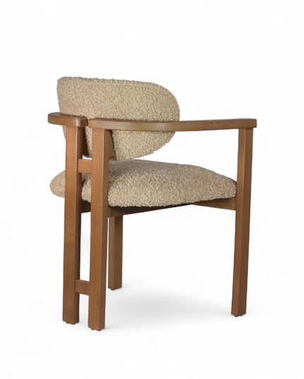 Modern wooden chair with beige boucle upholstery, featuring cushioned seat, rounded backrest, and minimalist armrests.
