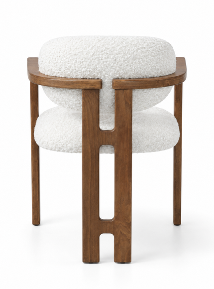 A modern accent chair featuring a warm brown wooden frame with a unique cutout design on the legs, paired with plush white bouclé fabric cushions on the seat and backrest, shown against a solid white background.