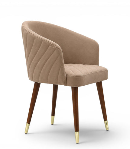 A modern dining chair with a curved, tufted backrest and seat upholstered in a warm taupe-beige fabric, supported by four tapered dark brown wooden legs with gold metal caps, shown against a plain white background.