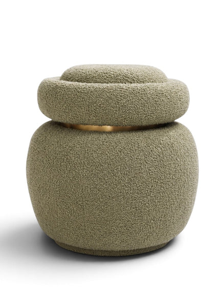 A modern textured pouf or small stool with a matching lid, upholstered in a bouclé-like fabric in a muted sage green color, featuring a thin gold metallic accent ring around the middle, set against a plain white background.