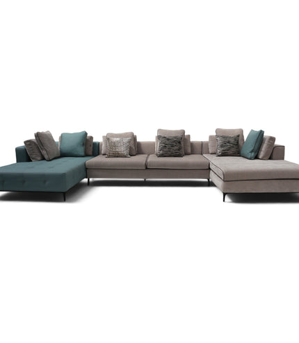 A modern sectional sofa with a left chaise in teal and taupe, accented with patterned and solid throw pillows, photographed against a solid white background.
