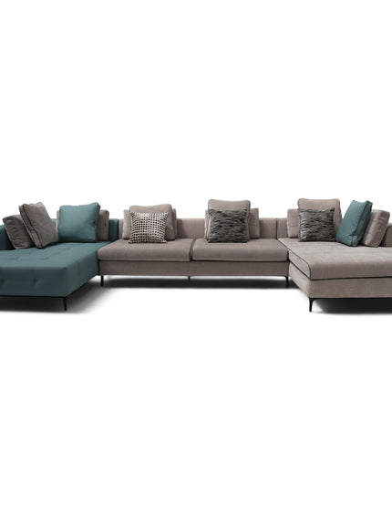 A modern sectional sofa with a left chaise in teal and taupe, accented with patterned and solid throw pillows, photographed against a solid white background.