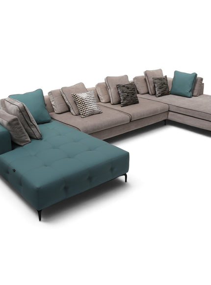An U-shaped sectional sofa in a light taupe fabric, featuring a tufted chaise lounge in teal on the left and multiple matching and patterned throw pillows, shown on a plain white background.
