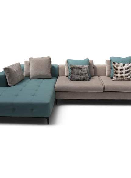 A modern sectional sofa with a tufted chaise lounge in teal and taupe, styled with several decorative throw pillows, shown against a plain white background.