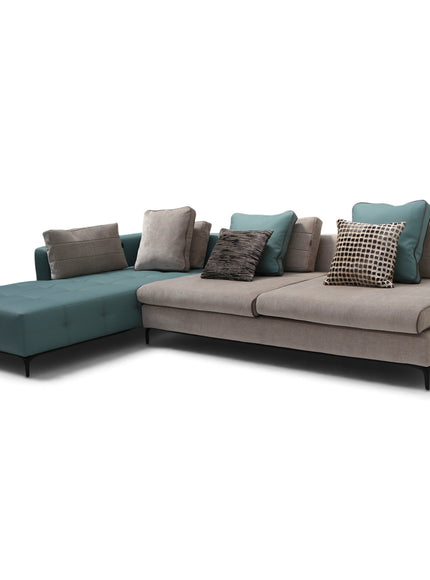 A modern sectional sofa with a left-facing chaise lounge, upholstered in a light taupe fabric with teal blue cushions and several decorative throw pillows, shown against a plain white background.