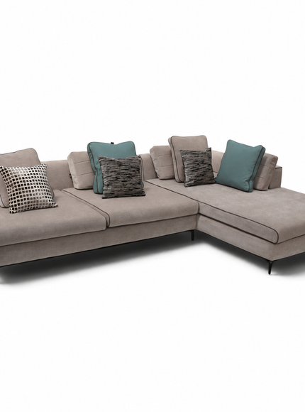 A modern L-shaped sectional sofa upholstered in a textured taupe fabric, styled with multiple throw pillows including teal and patterned designs, set against a plain white background.