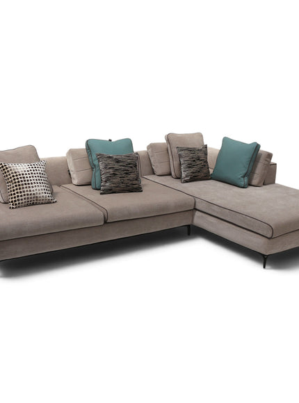 A modern L-shaped sectional sofa upholstered in a textured taupe fabric, styled with multiple throw pillows including teal and patterned designs, set against a plain white background.