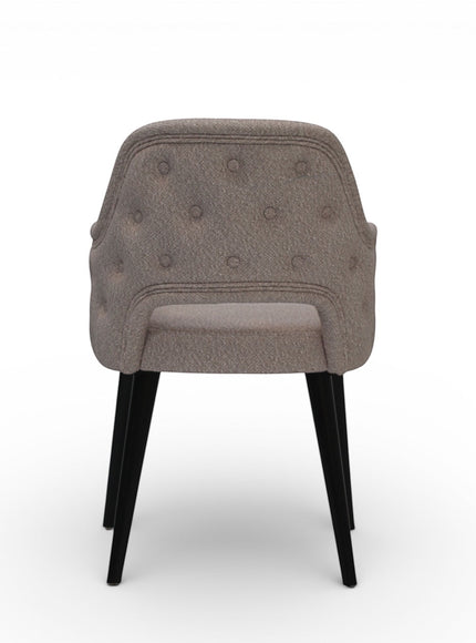 Back view of the Vaya Home Alt dining chair with beige upholstery, button-tufted outer back, and black tapered legs.