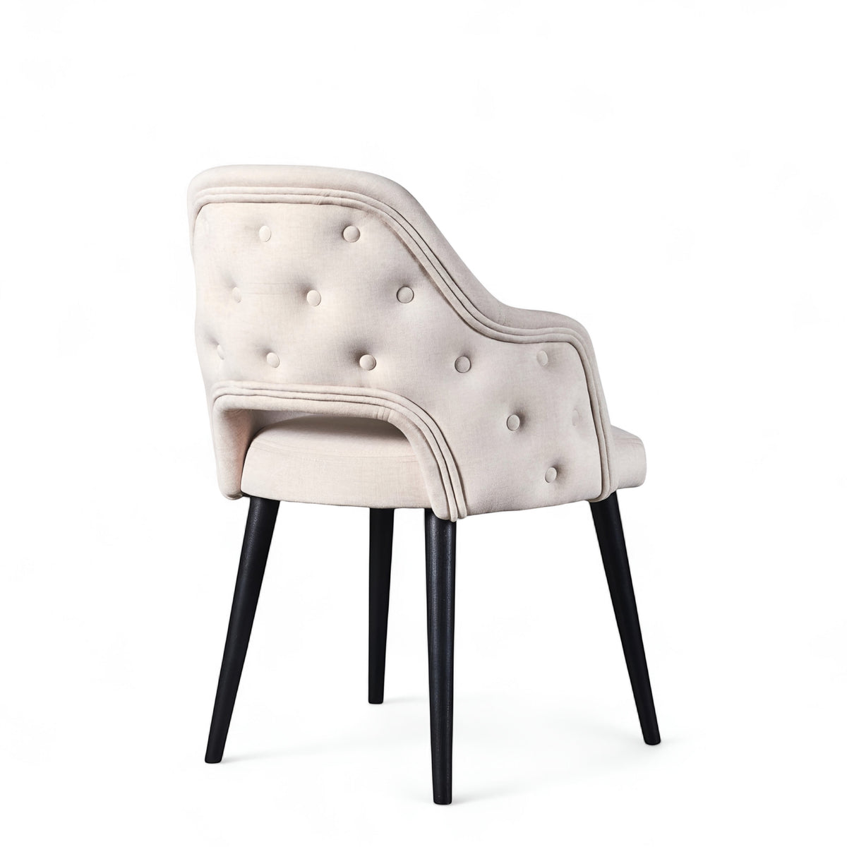 Rear angled view of the Vaya Home Alt dining chair with white upholstery, button-tufted outer back, curved arms, and black tapered legs.