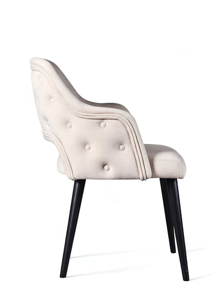 Side rear view of the Vaya Home Alt dining chair featuring white upholstery, a curved button-tufted back, and black tapered legs.