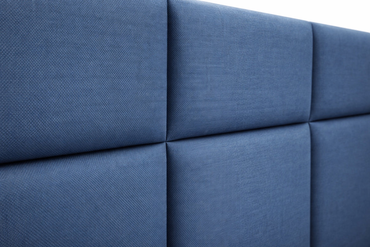 Close-up of the Vaya Home Alturo bed headboard showing blue upholstered panels and stitched detailing.