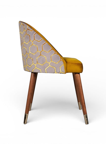 Side view of the Vaya Home Alveare dining chair with yellow seat upholstery, gray geometric patterned outer back, and tapered wood legs.