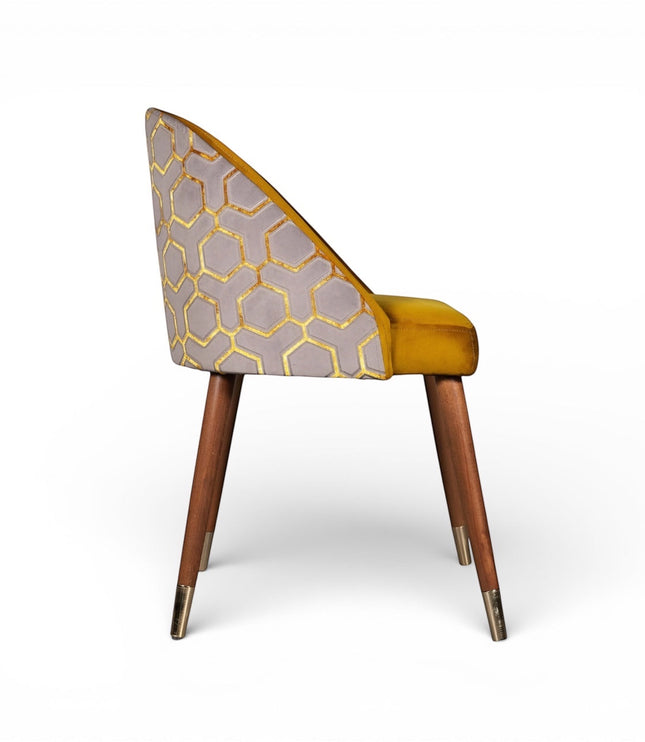 Side view of the Vaya Home Alveare dining chair with yellow seat upholstery, gray geometric patterned outer back, and tapered wood legs.