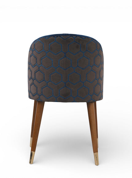 Back view of the Vaya Home Alveare dining chair featuring navy upholstery with a geometric patterned outer back and tapered wood legs.