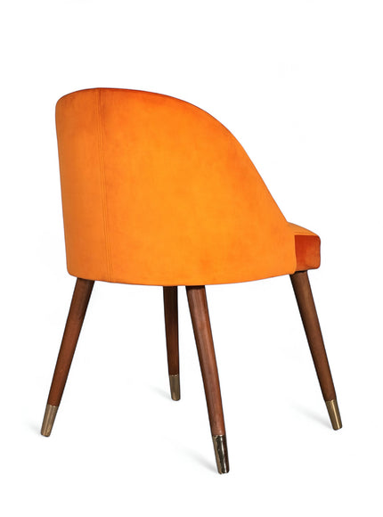 Rear angled view of the Vaya Home Alveare dining chair with orange upholstery and tapered wood legs.