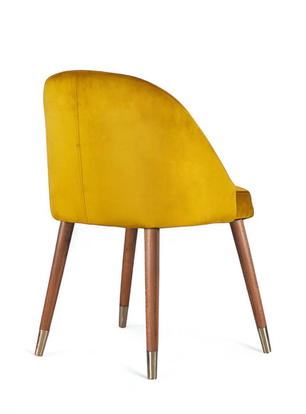 Rear angled view of the Vaya Home Alveare dining chair with yellow upholstery and tapered wood legs.