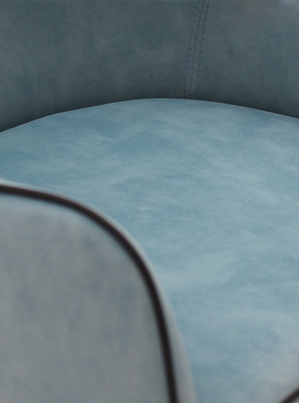 Close-up of the Vaya Home Alven dining chair showing blue upholstery, piped edge detailing, and seat texture.
