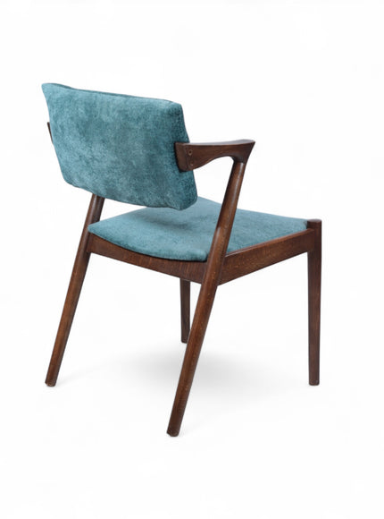 Rear angled view of the Vaya Home Angolo dining chair featuring blue upholstery, angled wood arms, and a dark wood frame.