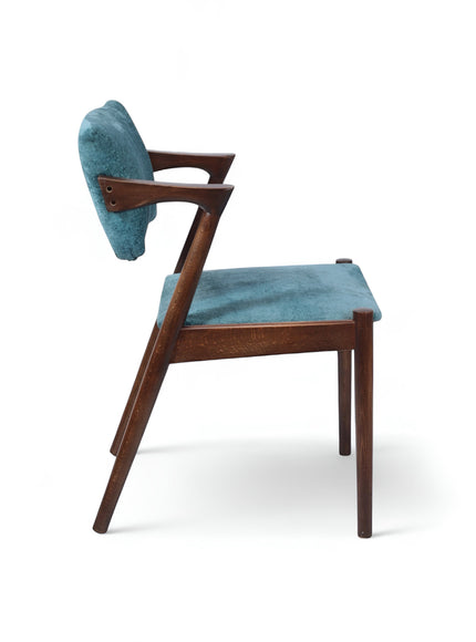 Side view of the Vaya Home Angolo dining chair with blue upholstery, angled wood arms, and a dark wood frame.