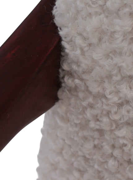 Close-up of the Vaya Home Angolo dining chair showing white boucle upholstery and dark wood frame detail.