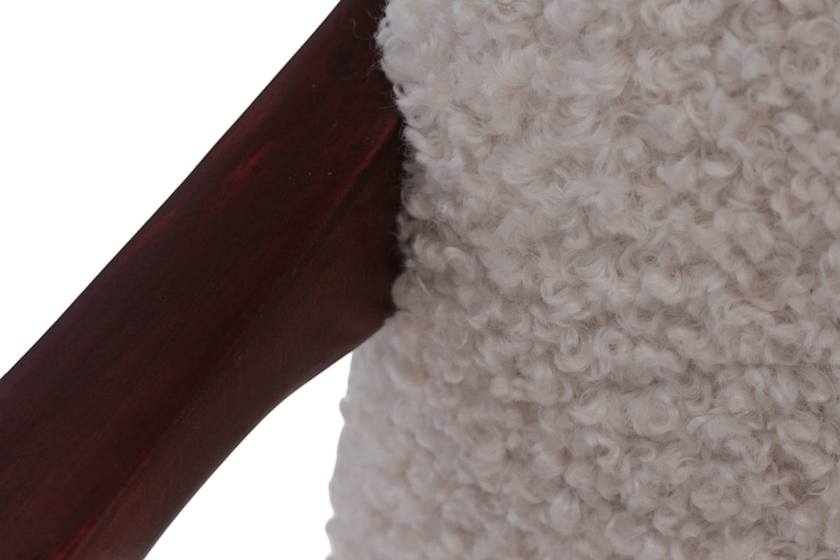 Close-up of the Vaya Home Angolo dining chair showing white boucle upholstery and dark wood frame detail.